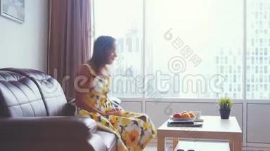 年轻漂亮的女人在家里的皮革沙发上放松，看电影，喝茶。 3840x2160